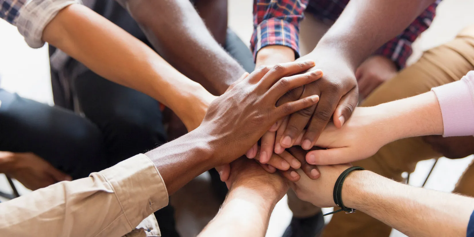 A group of people with their hands stacked on top of each other in a circle.